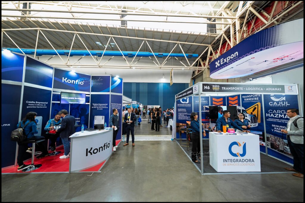 Pasillos con stands de diversas empresas en la Expo Pyme Bajío 2025, celebrada en Poliforum León, Guanajuato. Se observan visitantes interactuando con expositores en un entorno de negocios.
