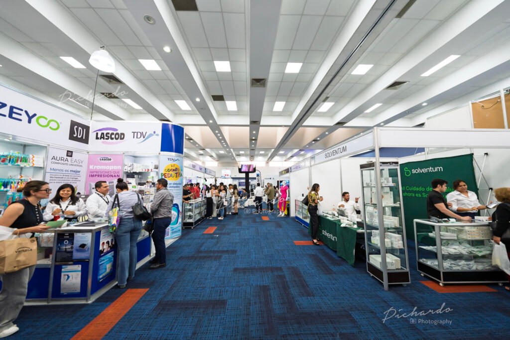 Área de exposición comercial en el congreso Dento León UNAM 2025, con asistentes interactuando en los stands de marcas odontológicas.
