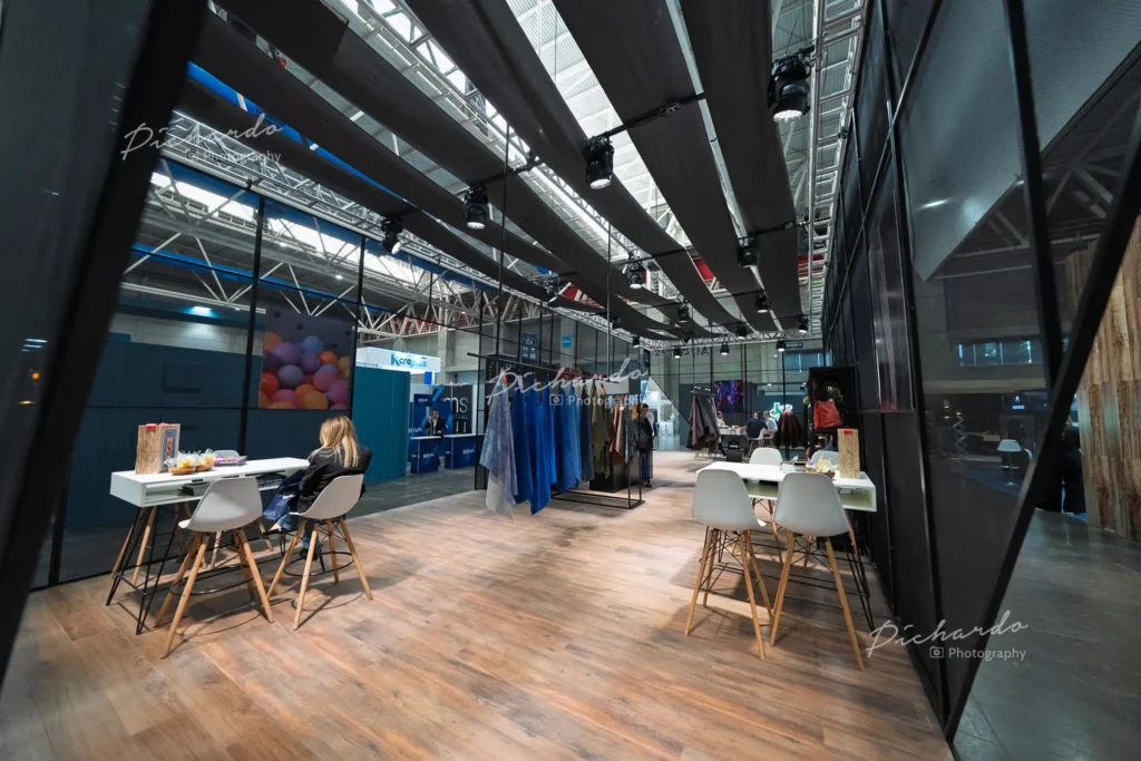 Stand moderno con piso de madera y mesas altas en la feria de proveeduría ANPIC Octubre 2025 en Poliforum León.