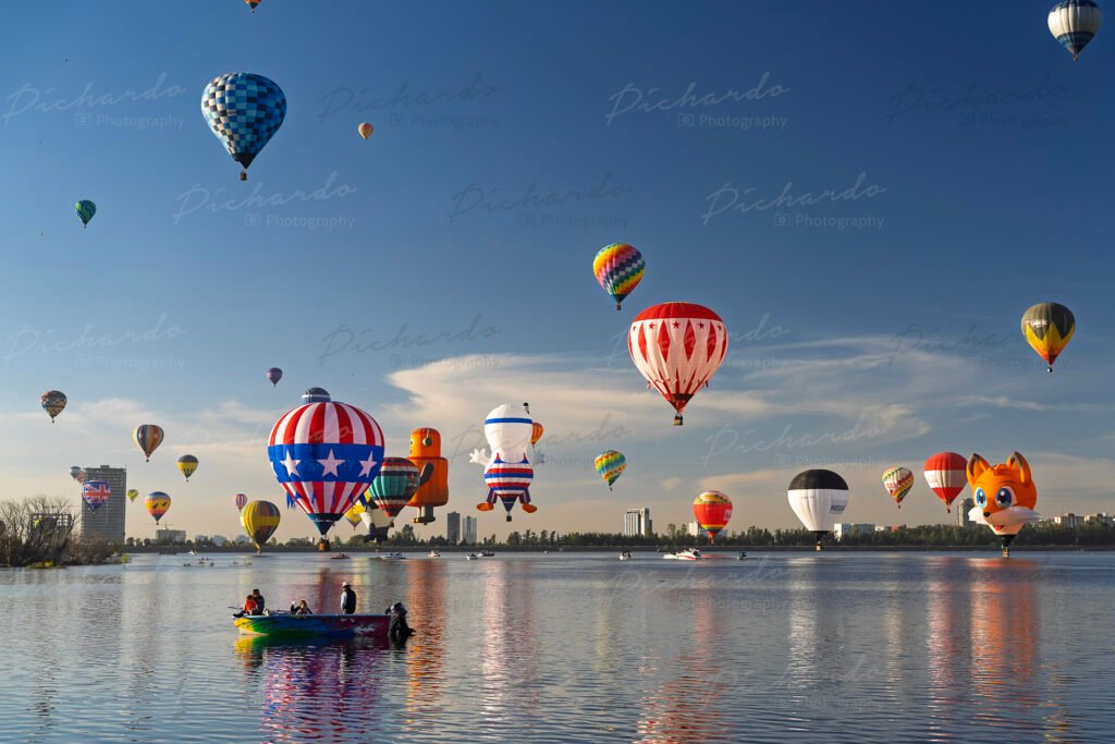 Despegue masivo en el Festival del Globo León 2025, con globos aerostáticos de un zorro y uno con la bandera de Estados Unidos sobre el lago.