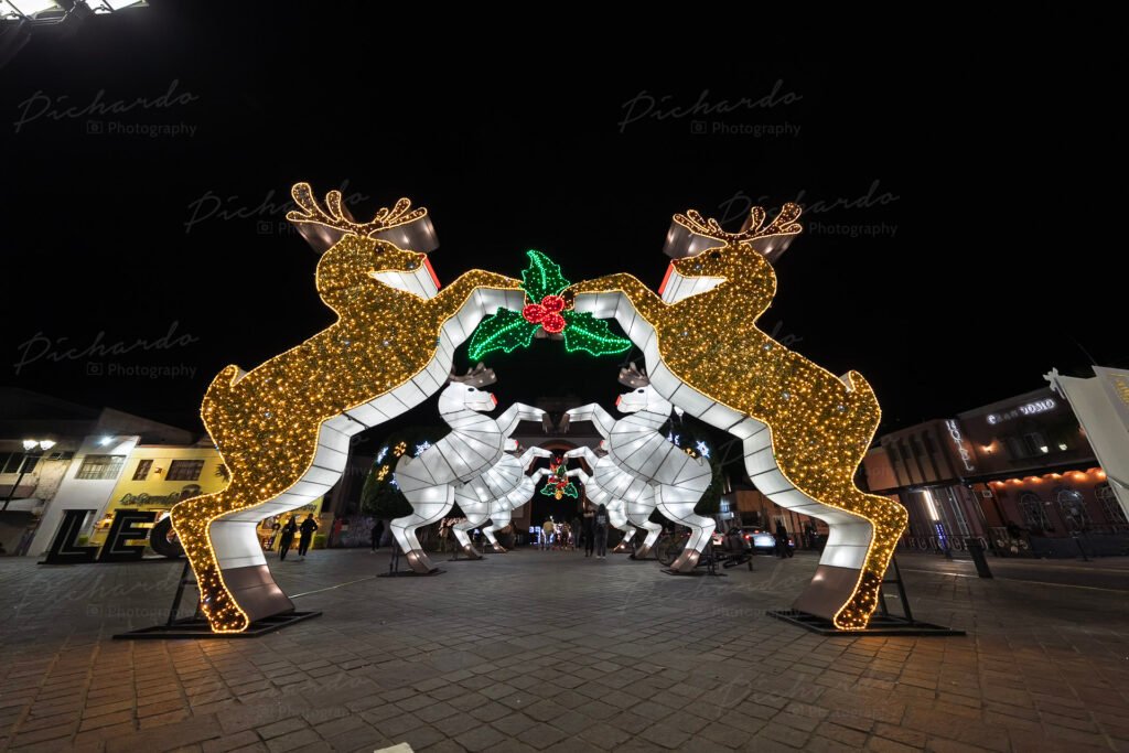 Figuras gigantes de renos iluminados formando un arco sobre la calzada en el centro de León.