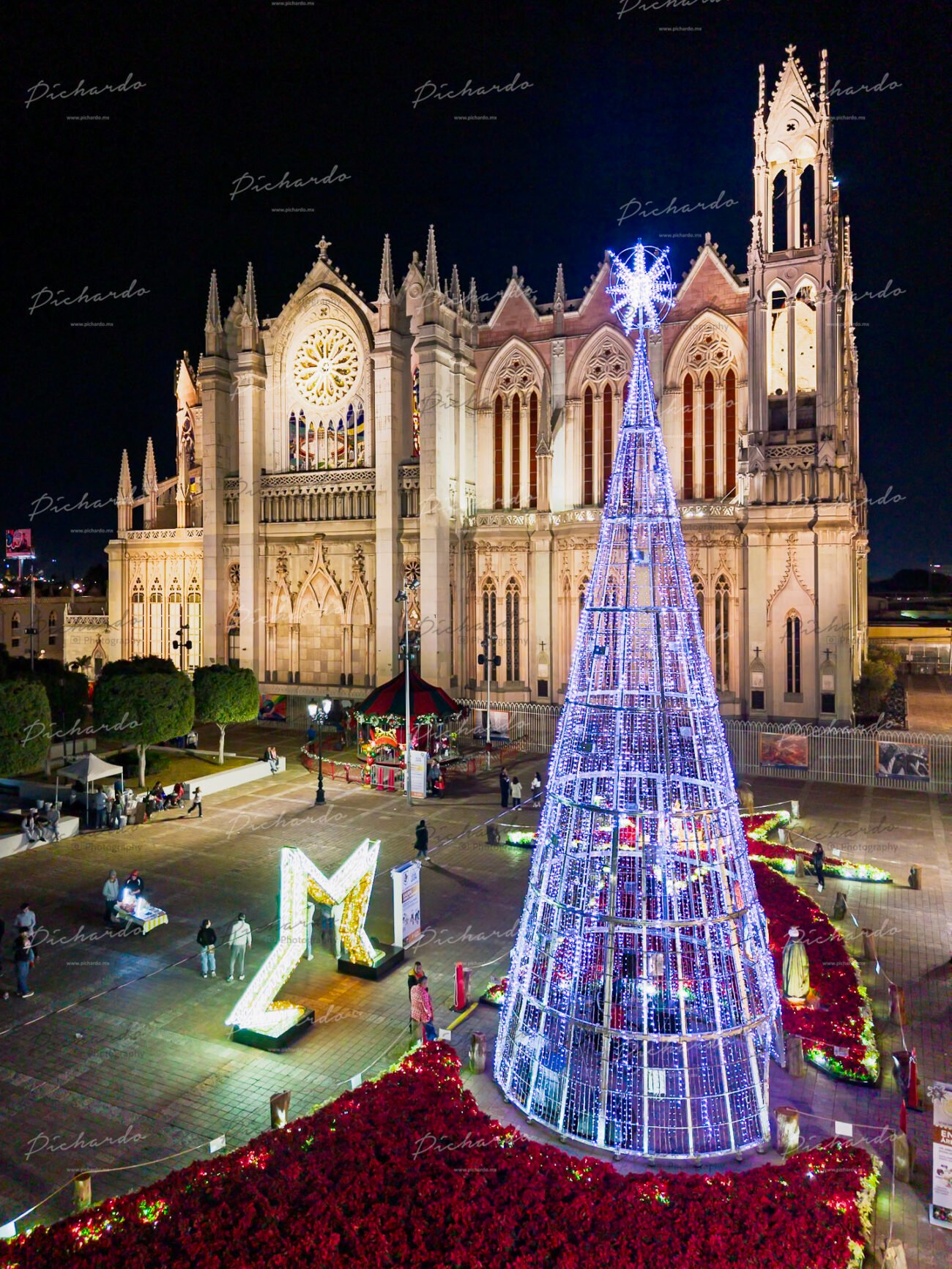 Vista aérea del Templo Expiatorio de León iluminado junto a un gran árbol de navidad LED azul.