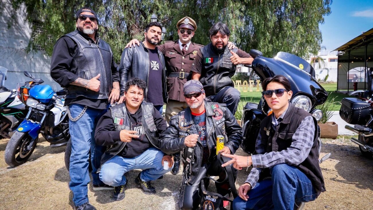 Grupo de motociclistas del motoclub Desterrados y personaje de tránsito vintage posando junto a motos en Motofiesta León.