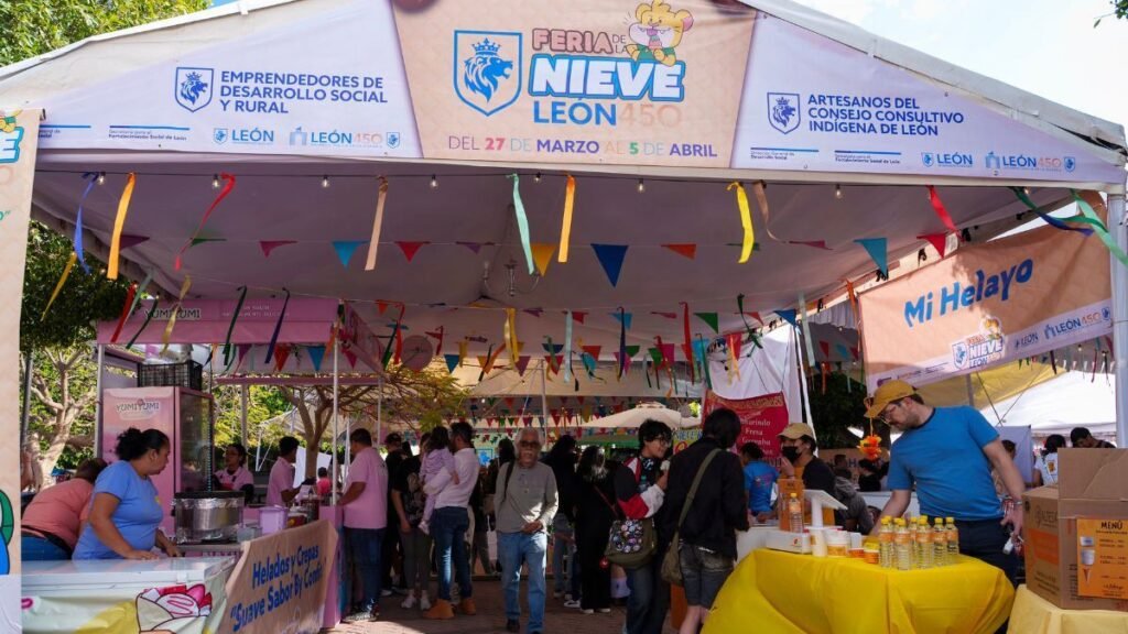 Familias leonesas recorriendo los stands bajo la carpa principal de la Feria de la Nieve León 2026, decorada con banderines de colores.
