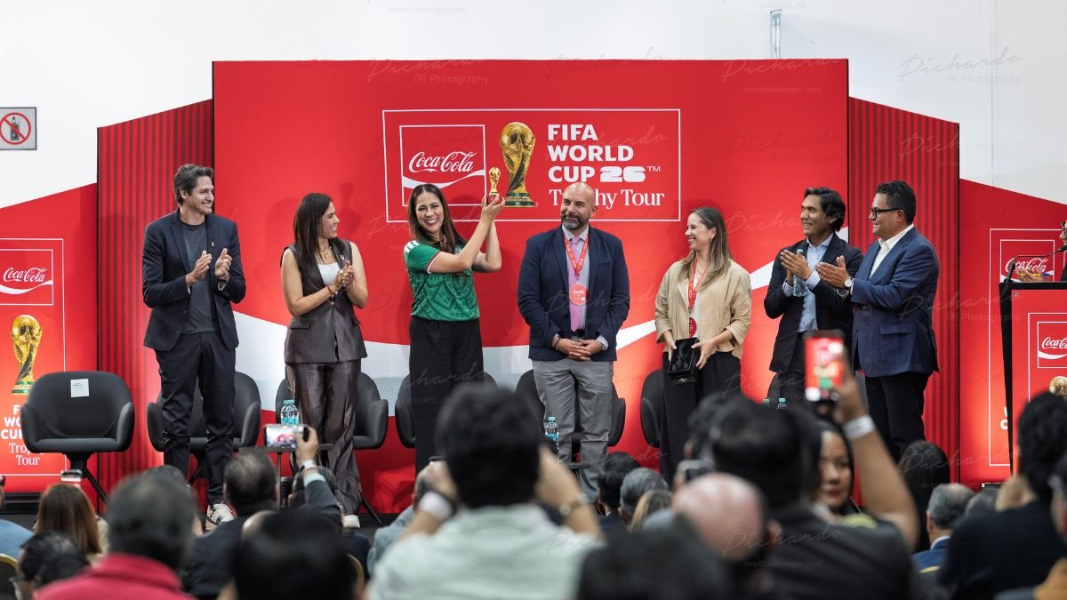 Libia Dennise Muñoz Ledo, Ale Gutiérrez y Edmílson en el escenario durante la presentación del Trophy Tour León 2026 de la Copa Mundial de la FIFA en Poliforum León.