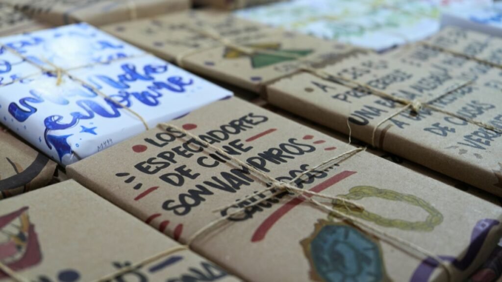 Libros envueltos en papel kraft con frases literarias escritas a mano y atados con hilo, listos para la dinámica de libros sorpresa en la FENAL León.